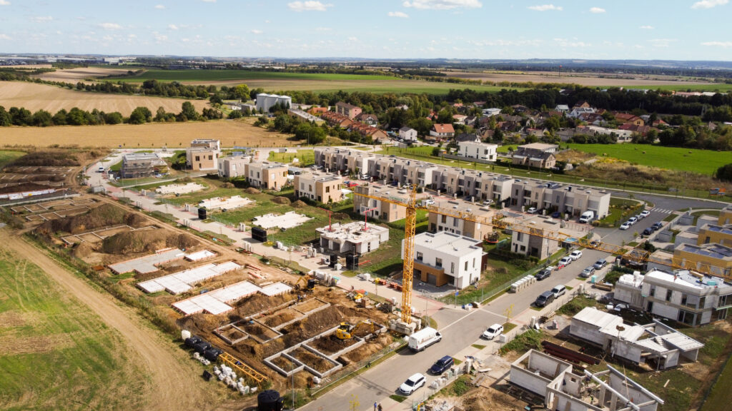 Letecký pohled na moderní rodinné domy v Horních Počernicích, rozvíjející se rezidenční čtvrť s novostavbami a okolní zelení na východě Prahy.