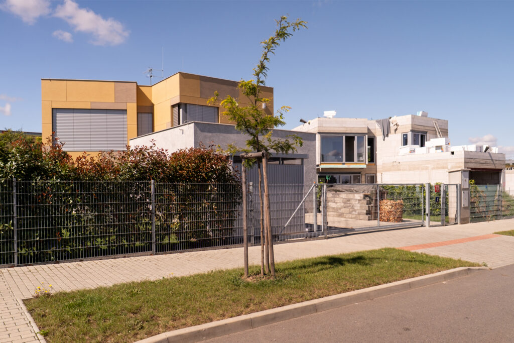 Moderní novostavba rodinného domu v developerském projektu Domy Bílý Vrch v Praze – klidná ulice, zeleň a moderní architektura.