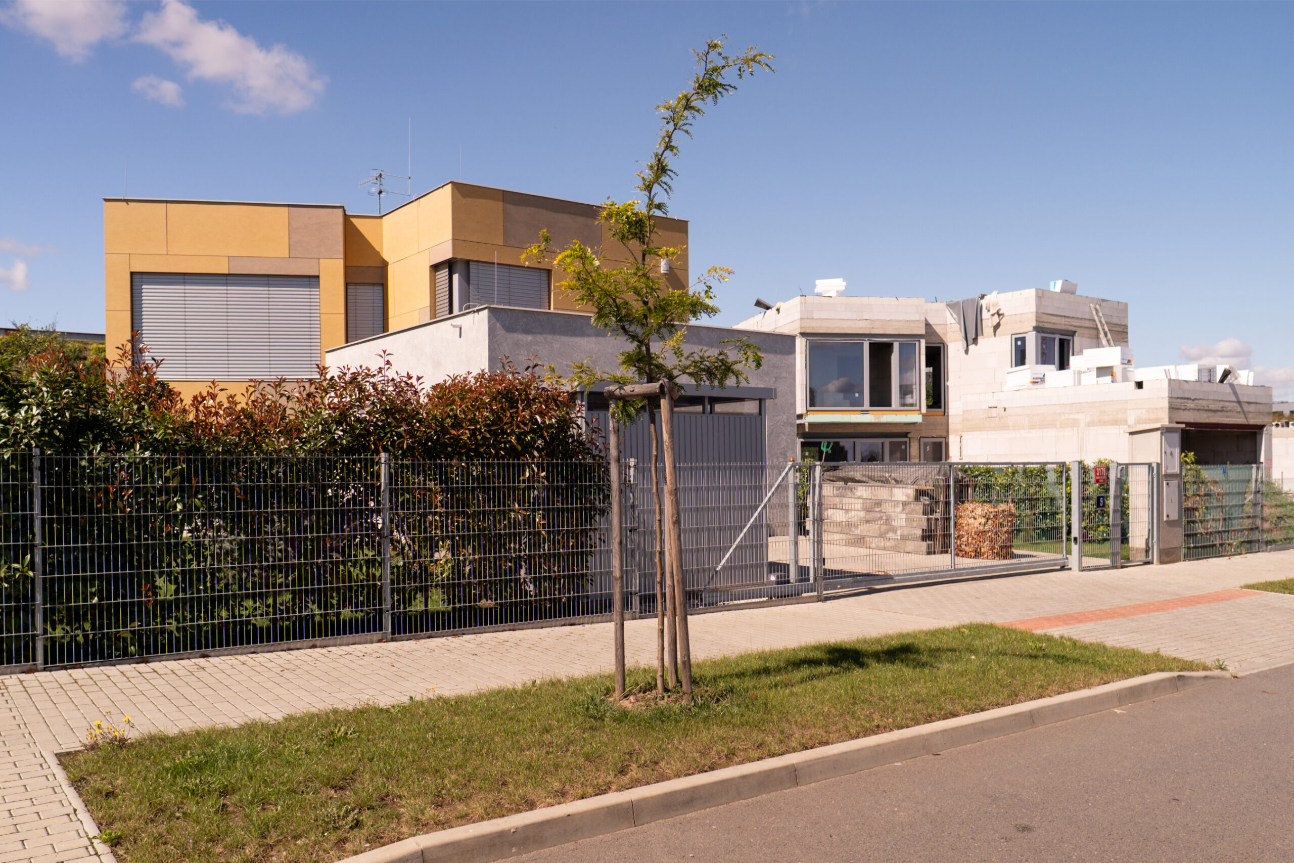 Moderní novostavba rodinného domu v developerském projektu Domy Bílý Vrch v Praze – klidná ulice, zeleň a moderní architektura.